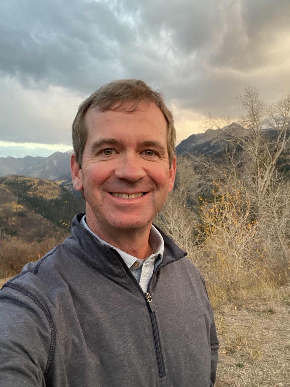 David McElyea, founder of Western Slope AI, outdoors with mountains behind him.